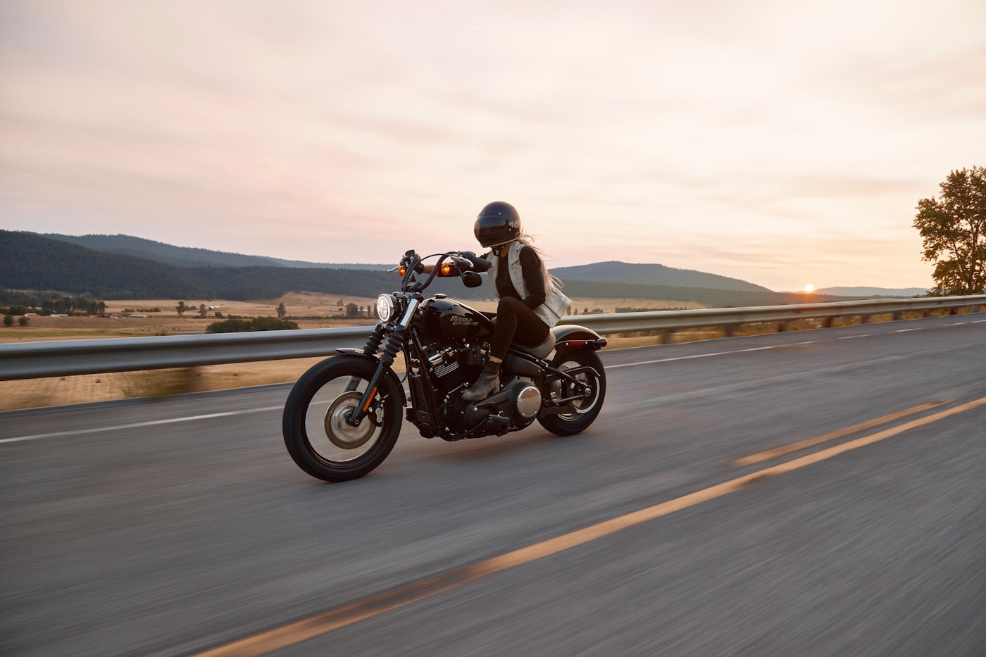 Motorcycle rider on highway at sunset
